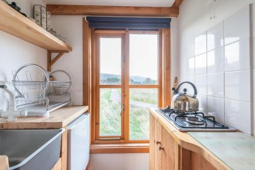 a kitchen with a stove top oven next to a window at The Field House in Fort Augustus