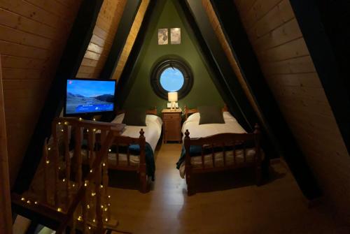 a attic room with two beds and a television at Apartamentos Boabdil in Sierra Nevada