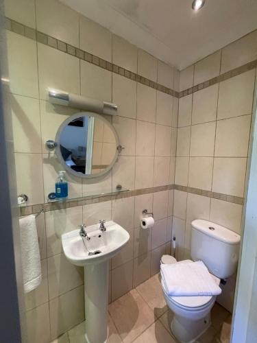 a bathroom with a sink and a toilet and a mirror at Oakhurst Gatwick B&B & bookable Holiday parking deals GATWICK transport in Crawley