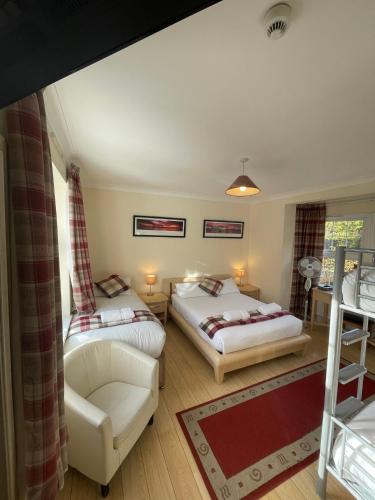 a bedroom with two beds and a couch and a chair at Oakhurst Gatwick B&B & bookable Holiday parking deals GATWICK transport in Crawley