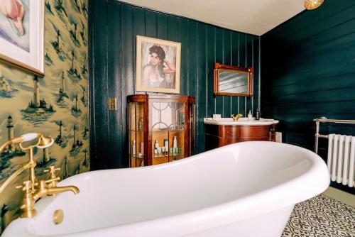 a bathroom with a white tub and a green wall at The Wellie Stern a unique home recapturing history in Harwich