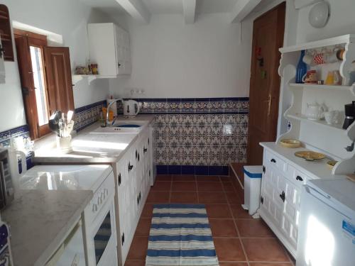 a kitchen with white cabinets and a tile floor at Casa 44, Delightful rural cottage with pool. in Lubrín