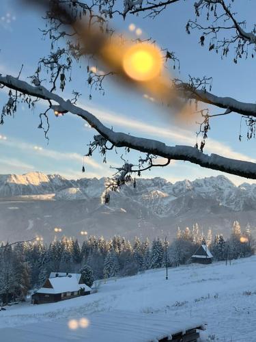 a winter view of a snowy mountain with the sun in the sky at Mała Bawaria in Zakopane