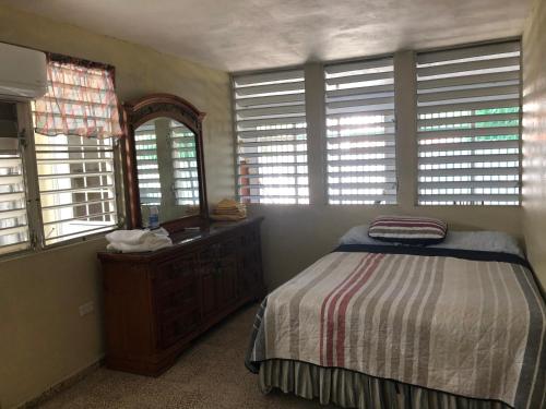 a bedroom with a bed and a dresser and windows at Guanica Malecon Bay House in a comfortable and quiet place in Guanica