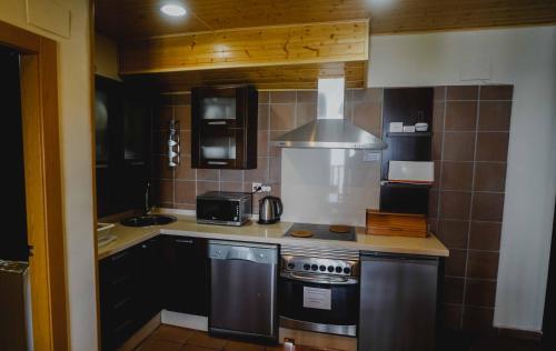 a small kitchen with a stove and a microwave at Apartamentos Boabdil in Sierra Nevada