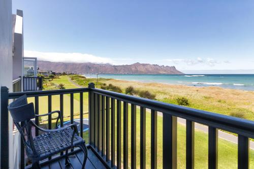 a bench sitting on a balcony overlooking the ocean at Strand Beach Lodge in Strand