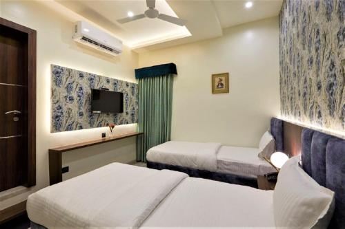 a hotel room with two beds and a tv at Hotel Rose Gold in Ahmadnagar