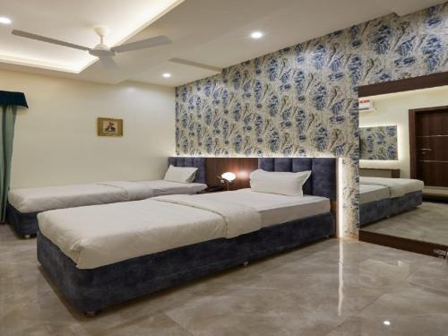 two beds in a room with blue and white wallpaper at Hotel Rose Gold in Ahmadnagar