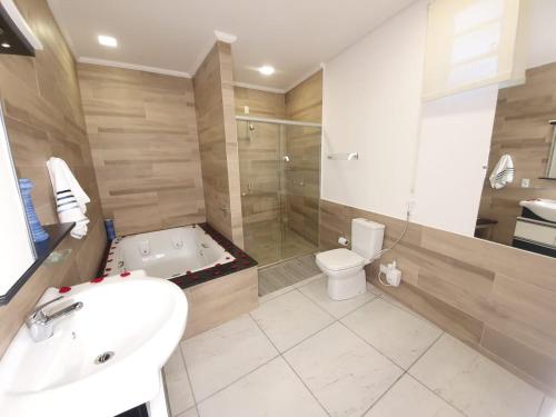 La salle de bains est pourvue d'une baignoire, de toilettes et d'un lavabo. dans l'établissement Chacara bora bora, à São Bento do Sapucaí