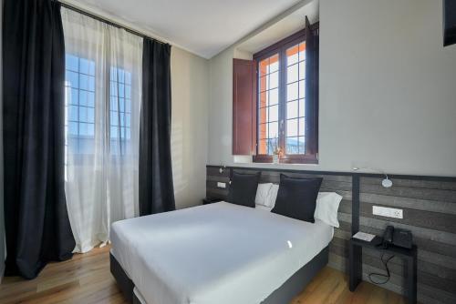 a bedroom with a large white bed and a window at Hotel Parada Puigcerda in Puigcerdà