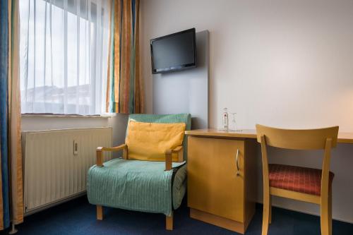 a room with a chair and a desk and a tv at acora Karlsruhe Zentrum Living the City in Karlsruhe