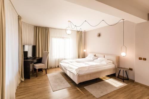 ein Schlafzimmer mit einem weißen Bett, einem Schreibtisch und einem Stuhl in der Unterkunft Villa V in Braşov