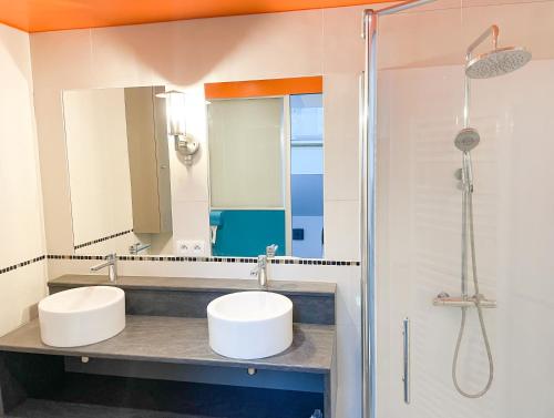 a bathroom with two sinks and a shower at Bel appartement contemporain in Alençon