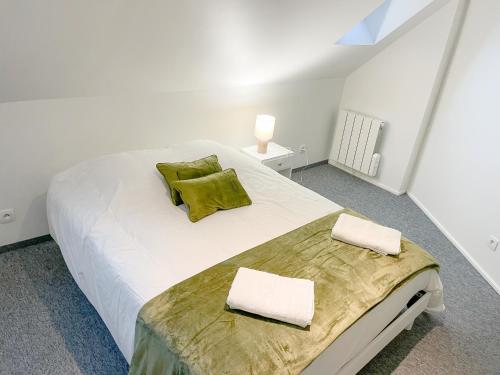 a bedroom with a large white bed with green pillows at Bel appartement contemporain in Alençon