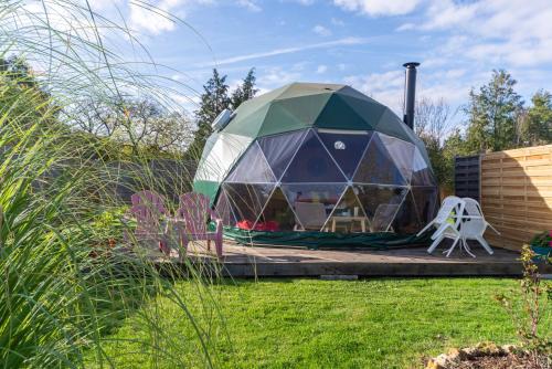 a dome tent in a garden with a chair at Le Nid du Tui in Faverolles