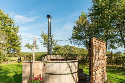 a garden with two wooden barrels and a stone wall at Le Nid du Tui in Faverolles