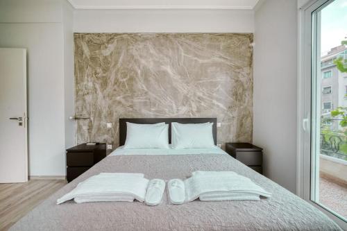 Charming Contemporary 2 bedroom apartment في أثينا: غرفة نوم بسرير وفوط بيضاء وحذاء