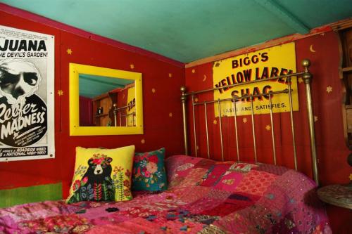 a bedroom with a bed and posters on the wall at Surfers and walkers cosy camping cabin in Ilfracombe