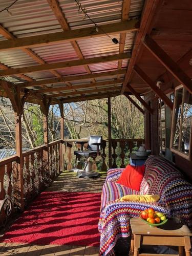 a covered porch with a couch and a bowl of fruit on a table at Surfers and walkers cosy camping cabin in Ilfracombe