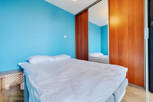 ein Schlafzimmer mit einem Bett und einer blauen Wand in der Unterkunft Loft Marmurowy by LookAp in Łódź