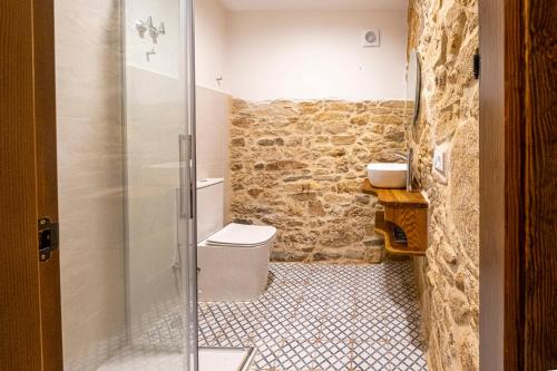 a bathroom with a toilet and a glass shower at Casa Rural Laxido in Rianjo