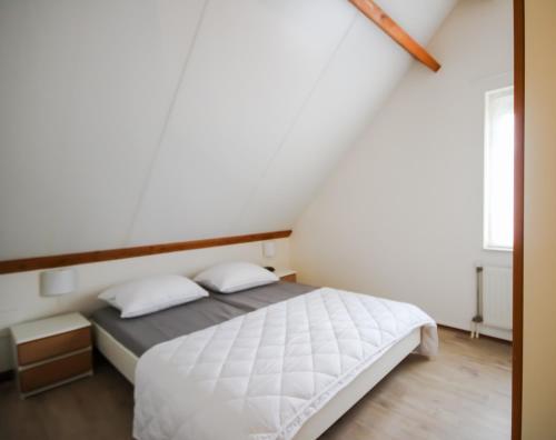 a bedroom with a bed with white sheets at Huisje 11 Wemeldinge in Wemeldinge