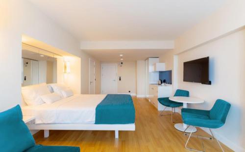 Batumi Next Sea Aparthotel في باتومي: غرفة نوم بسرير ابيض وكراسي زرقاء
