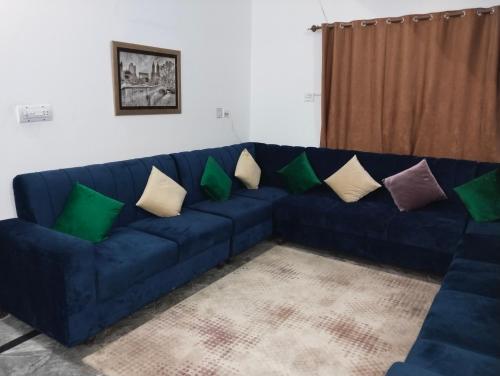 a blue couch with colorful pillows in a living room at Homewood Suites Family Guest House & Apartments in Lahore