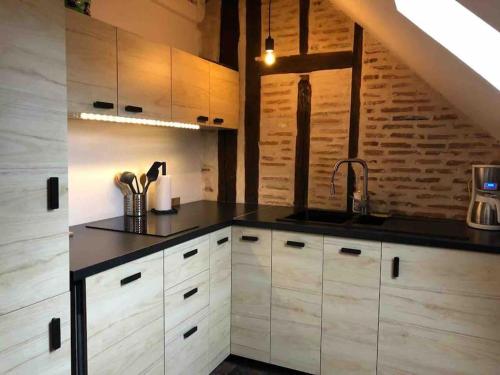 a kitchen with white cabinets and a black counter top at La Scellerie, le charme au cœur de Tours in Tours