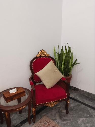 a red chair with a pillow and a table at Homewood Suites Family Guest House & Apartments in Lahore