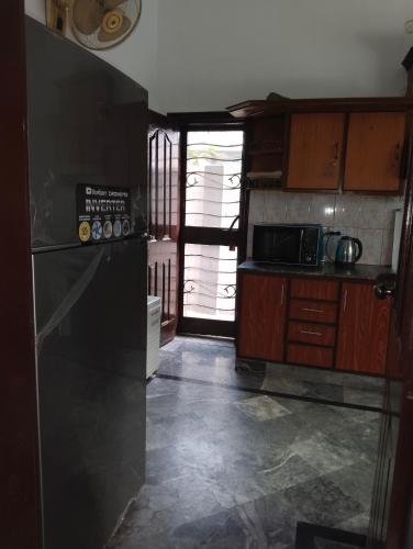 a kitchen with a black refrigerator and a microwave at Homewood Suites Family Guest House & Apartments in Lahore