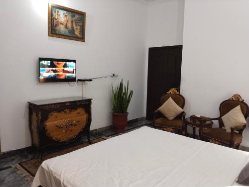a bedroom with a bed and two chairs and a fireplace at Homewood Suites Family Guest House & Apartments in Lahore