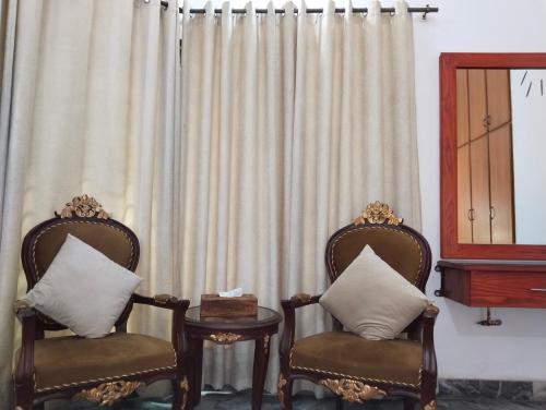 two chairs and a table in front of a curtain at Homewood Suites Family Guest House & Apartments in Lahore