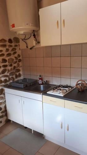 une cuisine avec des armoires blanches et une cuisinière dans l'établissement Gîte du figuier, à Fay-le-Clos