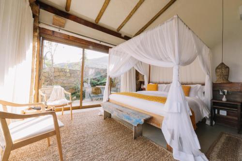 1 dormitorio con cama con dosel y silla en Casa Salga, en Ilhabela