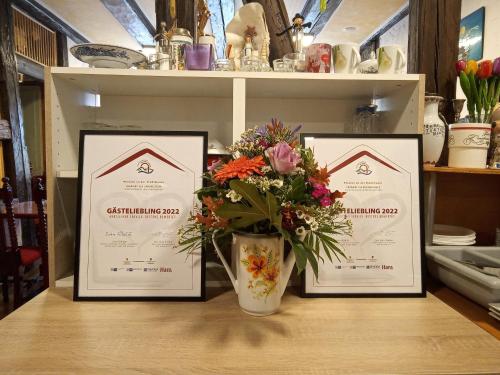 tres certificados enmarcados en una mesa con un jarrón de flores en Pension an der Stadtmauer Apartments, en Wernigerode