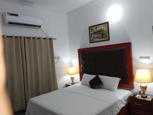 a bedroom with a bed with two lamps and a bed sidx sidx sidx at Homewood Suites Family Guest House & Apartments in Lahore