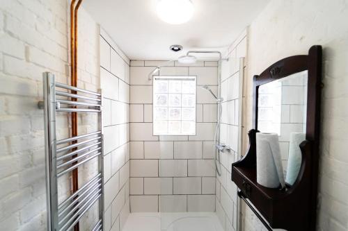 a white tiled bathroom with a shower and a mirror at Blue Sky Lodge in Overstrand