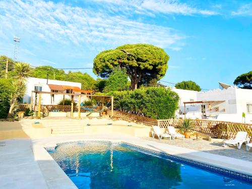 una piscina en un patio con sillas y un árbol en Poniente, en Barbate