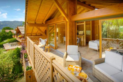 Cette maison en bois dispose d'un balcon avec des chaises et un lit. dans l'établissement Dorealp - OVO Network, à La Clusaz