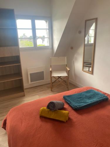a bedroom with a bed with two towels and a chair at La Brise Marine, calme, Océan, 350m plage in Loctudy