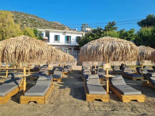 a group of lounge chairs and straw umbrellas on a beach at Big apartment on the beach in Tolo