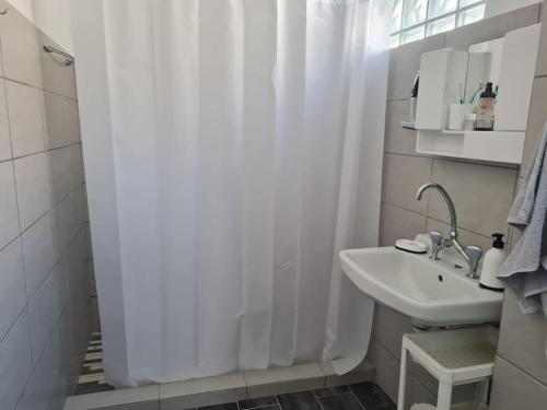 a white bathroom with a sink and a shower curtain at Big apartment on the beach in Tolo