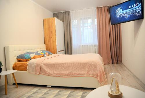 Schlafzimmer mit einem Bett und einem Flachbild-TV in der Unterkunft BoHo Apartment near Center! in Chişinău
