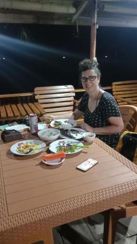 a woman sitting at a table with plates of food at Yohana Cottage in Tual
