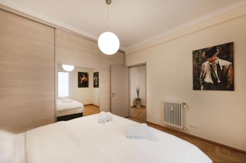 ein Schlafzimmer mit einem großen weißen Bett und einem Spiegel in der Unterkunft Kolonaki 2 Bdr apartment in Athen