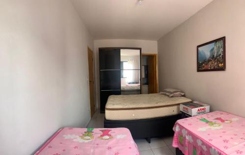 Cette petite chambre comprend 2 lits et 2 tables. dans l'établissement Apto Aconchegante, à Praia Grande
