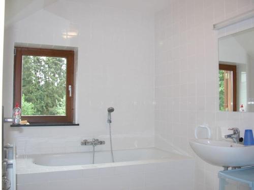 ein weißes Badezimmer mit einer Badewanne und einem Waschbecken in der Unterkunft Maison de vacances familiale: le Petit Nid Mosan in Dinant