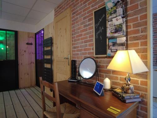 un escritorio con espejo y una lámpara. en HOTEL DU BERRY - Loveroom avec Sauna, Hammam, Jacuzzi privatifs, en Reuilly