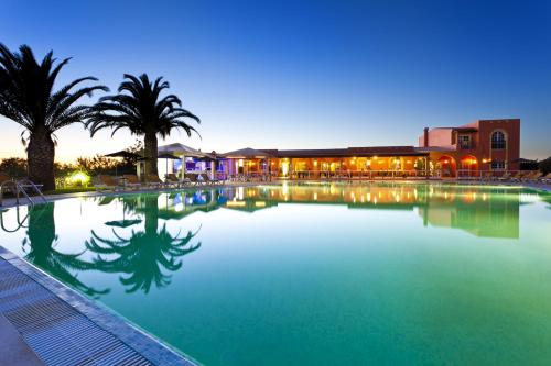 a large swimming pool with palm trees and a building at Colina Village in Carvoeiro